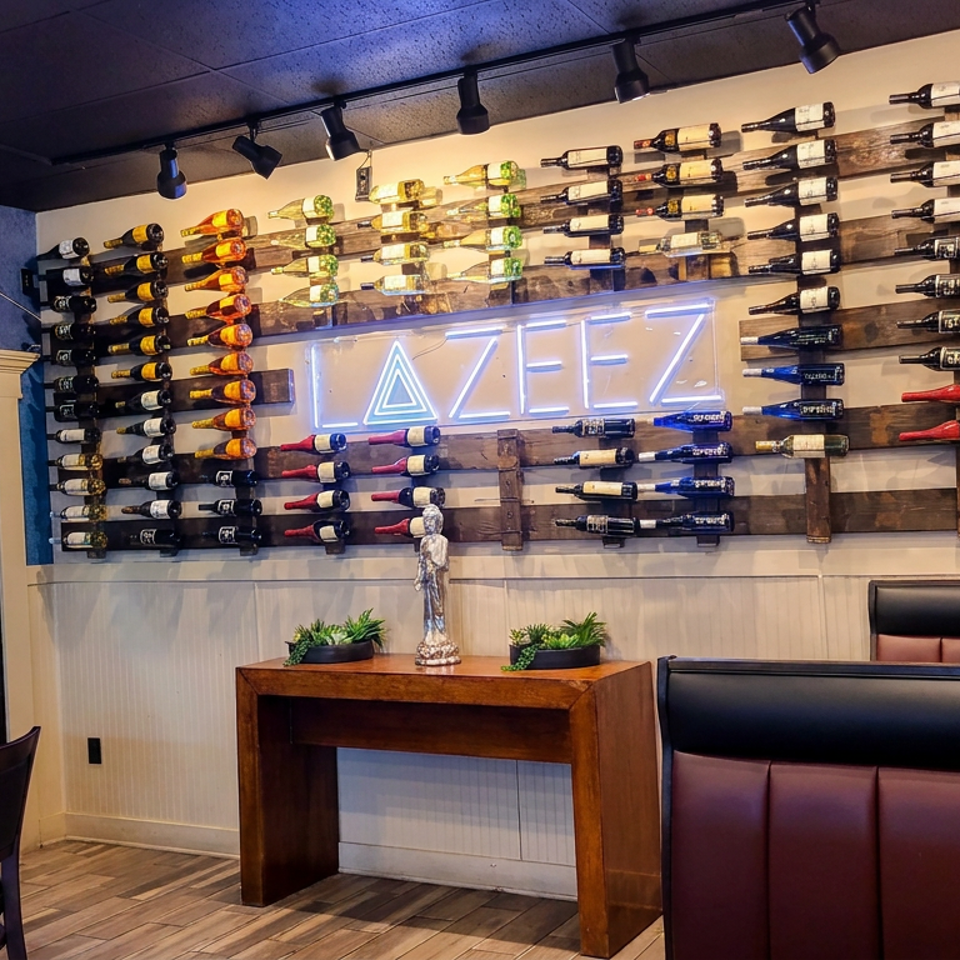 Upscale restaurant interior with rows of wine bottles displayed on wooden racks beneath a glowing AZEZ sign and leather booths.